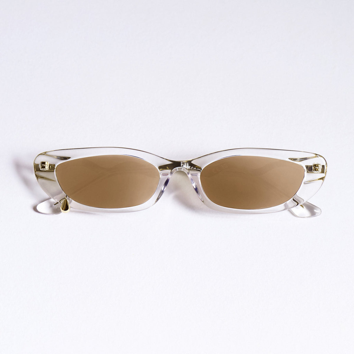 A pair of rimless cat-eye sunglasses with clear transparent frames and warm brown lenses, displayed on a clean white background.