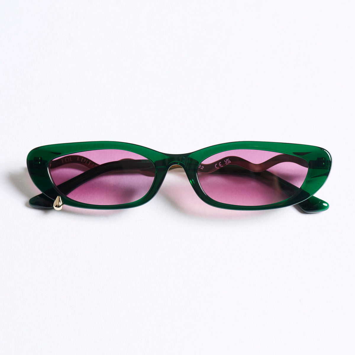 Cat-eye sunglasses with a translucent dark green acetate frame and pink-tinted lenses, photographed on a clean white background.